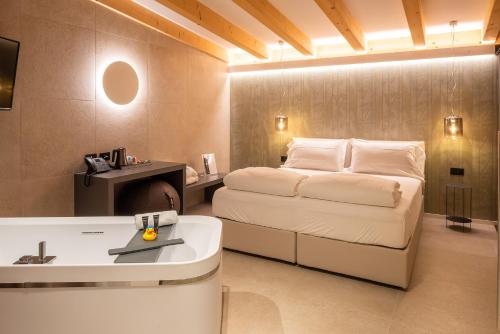 托里德尔贝纳科Relais Limonaia - Suites & Garden SPA的一间卧室配有一张床和一个水槽和一个浴缸