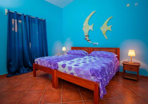 马约城Villa Lagosta Stella Maris Exclusive的一间卧室配有一张带紫色床单和蓝色墙壁的床。