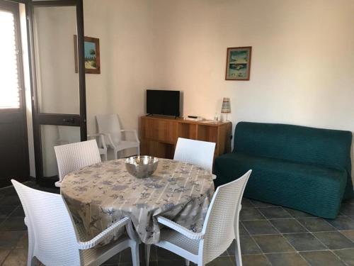 兰佩杜萨Appartamenti L'Approdo del Gabbiano的餐桌、白色椅子和绿色沙发