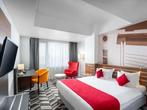 布加勒斯特布加勒斯特乌尼里美居酒店的酒店客房,配有一张床、一张桌子和椅子