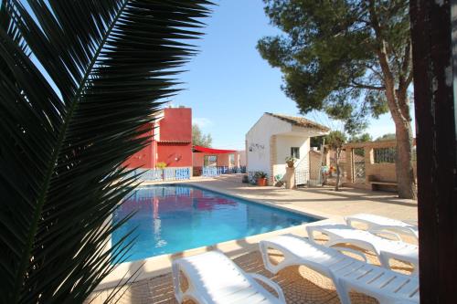 穆尔西亚Casa La Noria by Rental Olé的一个带白色椅子和棕榈树的游泳池