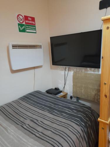 伦敦Bubblesbnb, 1 bedroom flat的一间卧室配有一张床和一台平面电视