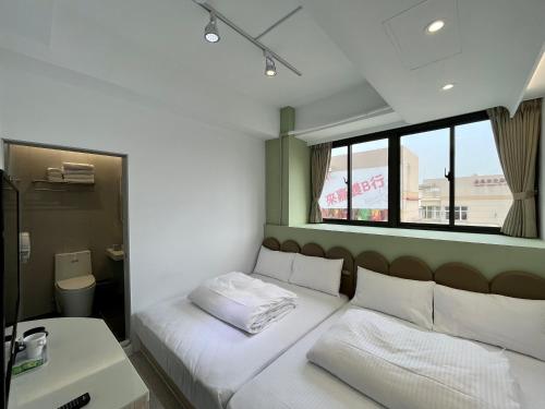 嘉义市享绽二三星球旅馆的一间卧室配有一张带白色床单的床和一扇窗户。