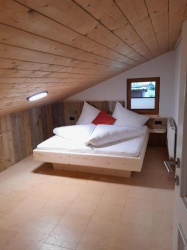 菲根贝格Wildauhof - Bauernhaus的一间卧室配有带白色床单和红色枕头的床。