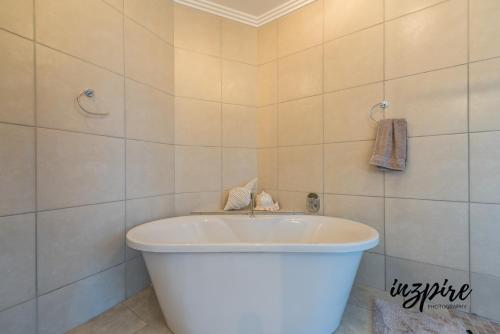 莫塞尔湾Gouriqua 401的浴室铺有白色瓷砖,配有白色浴缸。