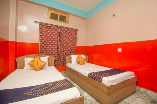 Alīpur DuārOYO Hotel Chitra的红色墙壁客房的两张床