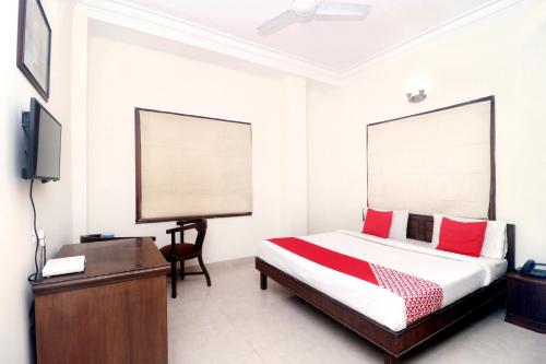 阿姆利则寺庙景酒店 的一间卧室配有一张床、一张书桌和一台电视