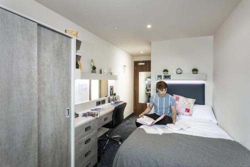 诺丁汉For Students Only Ensuite Bedrooms with Shared Kitchen at Triumph House in Nottingham的坐在卧室床上的男孩