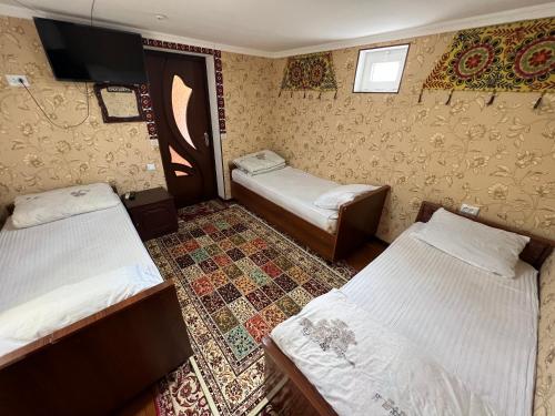 布哈拉''NAVO'' Guest House的客房设有两张床和一台墙上的电视。