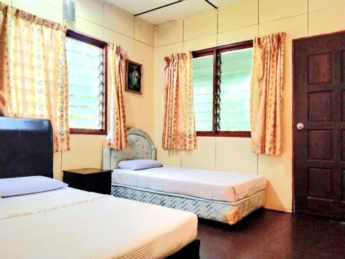 Sukau苏考背包客住宿加早餐旅馆的一间卧室设有两张床和一个门窗。