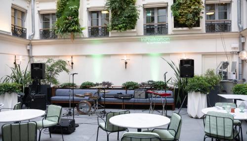 巴黎Kimpton - St Honoré Paris, an IHG Hotel的庭院配有桌椅和沙发。