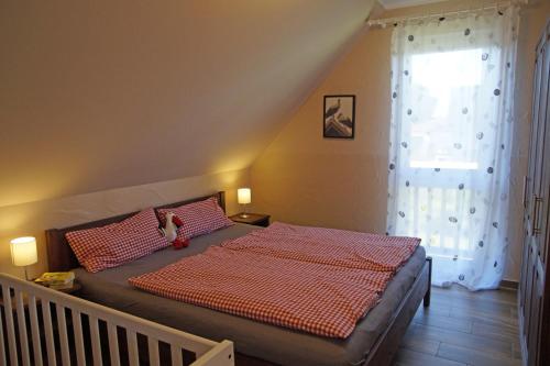 吕本Ferienwohnungen am Roten Nil的一间卧室配有一张带红色棉被的床和窗户。