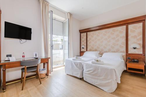阿拉西奥HOTIDAY Hotel Alassio的一间卧室配有两张床、一张桌子和一台电视。