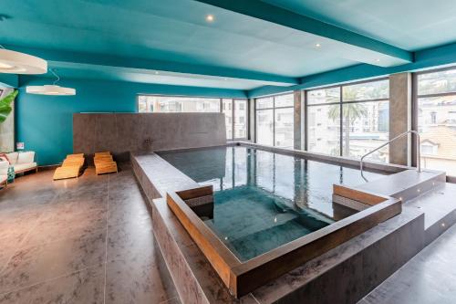 阿拉西奥HOTIDAY Hotel Alassio的蓝色天花板客房中间的热水浴池