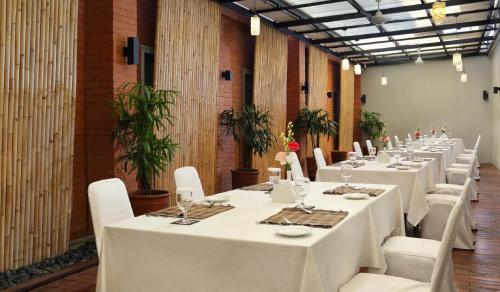 登巴萨吉兹会议酒店的配有白色桌子和白色椅子的长客房