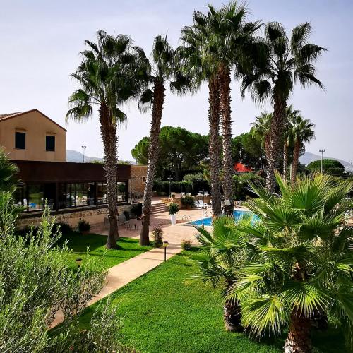 巴莱斯特拉泰Azienda Agrituristica Baglio Carta的棕榈树和游泳池度假村