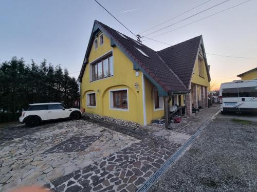格赖因Pension DonauBlick Grein 2 in Stifterstrasse 19A的一座黄色的房子,前面有一辆汽车