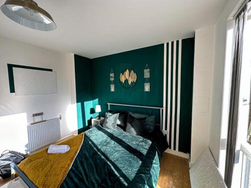 伦敦Comfortable Private Room in Bermondsey的一间卧室设有绿色的墙壁和一张带木桌的床
