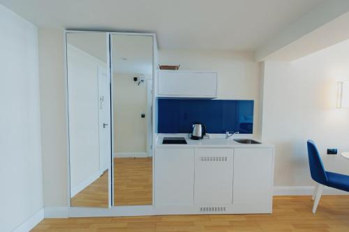 巴统ORBI CITY APART HOTEl的厨房配有白色橱柜和玻璃墙