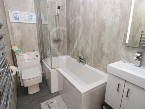 新港The Coach House的浴室配有卫生间、盥洗盆和浴缸。
