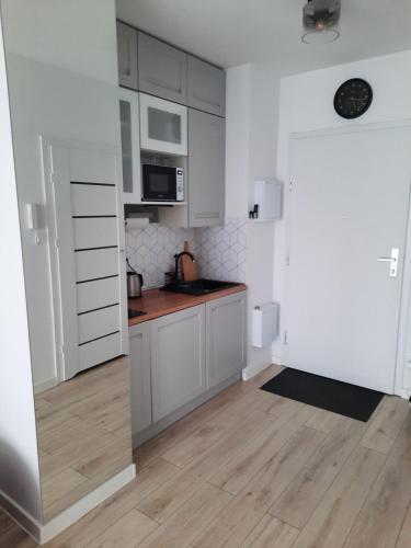 华沙George Studio przy Stadionie Narodowym的厨房铺有木地板,配有白色橱柜。