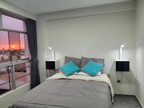 特鲁希略Apartamentos "APPART D'ELIETTE"的一间卧室配有一张带两个蓝色枕头的床