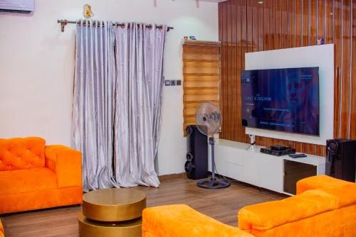 拉各斯Superb 2-Bedroom Duplex FAST WiFi+24Hrs Power的客厅配有橙色家具和平面电视。