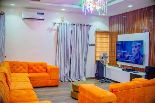 拉各斯Luxury 3-Bedroom Duplex FAST WIFI & 247Power的客厅配有橙色沙发和平面电视。