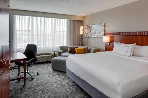 波士顿波士顿洛根机场万怡酒店的酒店客房配有一张床、一张书桌和一张沙发。