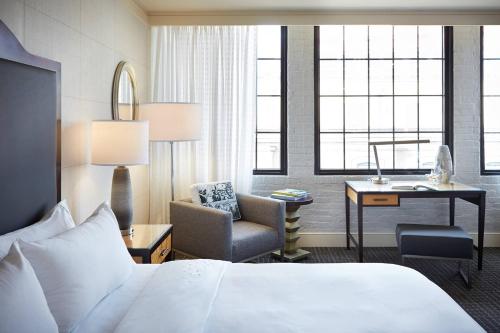 新奥尔良万豪奢华生活方式酒店 - 文艺复兴新奥尔良艺术仓库区酒店的酒店客房配有一张床、一把椅子和一张书桌