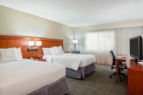 盖恩斯维尔Courtyard by Marriott Gainesville FL的酒店客房设有两张床和一台平面电视。
