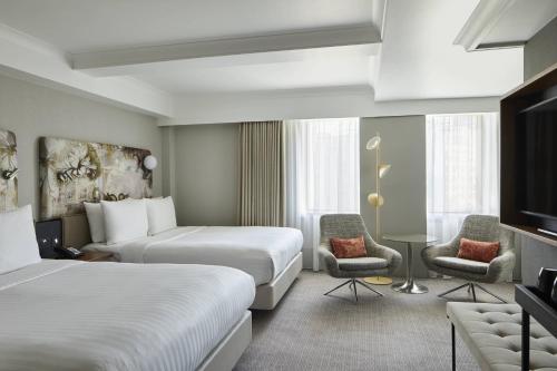 伦敦万豪伦敦肯辛顿度假酒店的酒店客房,配有两张床和两把椅子