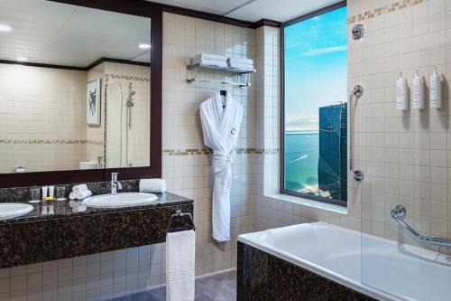迪拜朱美拉海滩华美达广场酒店的一间带两个盥洗盆、浴缸和窗户的浴室