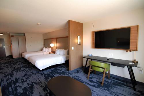 威诺纳Fairfield Inn & Suites Winona的酒店客房设有两张床、一张桌子和一台电视。