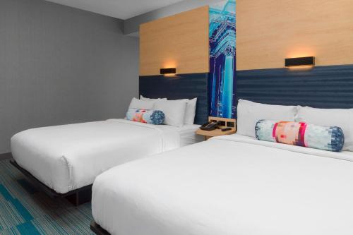 盖恩斯维尔Aloft Gainesville University Area的配有2张床铺的酒店客房,提供白色床单和枕头