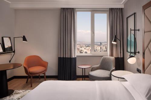 伊斯坦布尔Sheraton Istanbul Levent的酒店客房带床、椅子和窗户