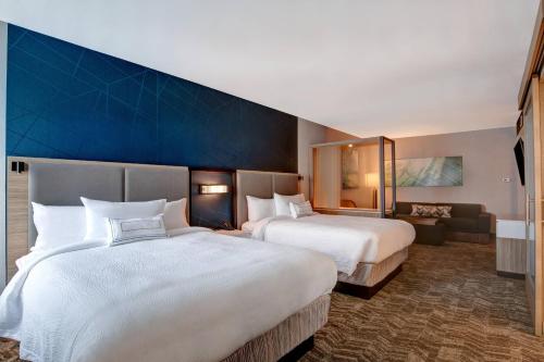 奥兰治堡SpringHill Suites by Marriott Orangeburg的酒店客房设有两张床和蓝色的墙壁。