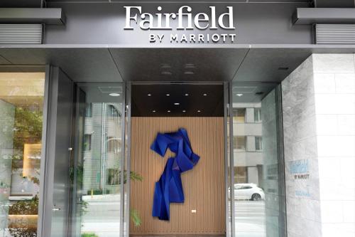 大阪Fairfield by Marriott Osaka Namba的建筑门上带有蓝色弓的标志