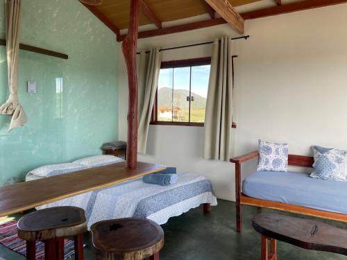 圣若热岛ninho da arara的一间卧室设有两张床、凳子和窗户。