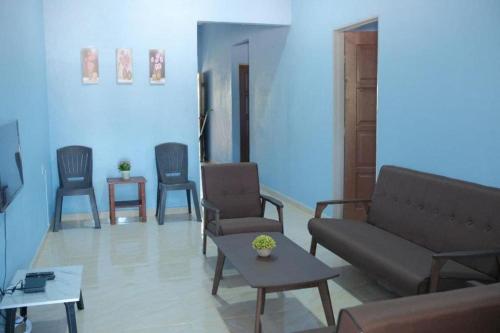 Kampong Wakaf TengahMufeed Homestay的客厅配有椅子、沙发和桌子