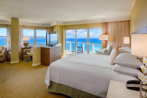 帕诺滩劳德代尔堡万豪帕诺海滩度假酒店&Spa的酒店客房配有一张床和一张书桌及一台电视