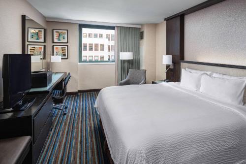 纽约纽约曼哈顿/时代广场万怡酒店的酒店客房配有一张床、一张书桌和一台电视。
