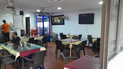 巴兰基亚Hotel Danes Barranquilla的一间带桌椅的餐厅以及墙上的电视