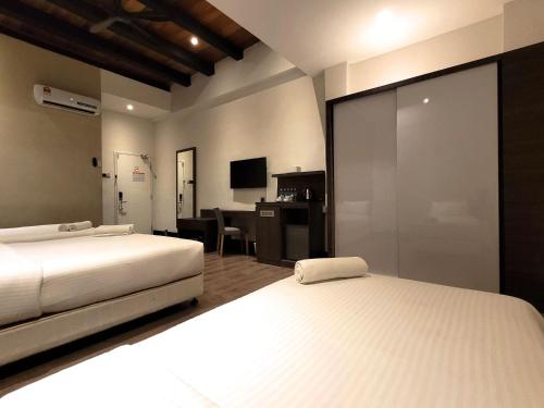 马六甲The NINES HOTEL Malacca的一间卧室配有两张床和一张带电脑的书桌