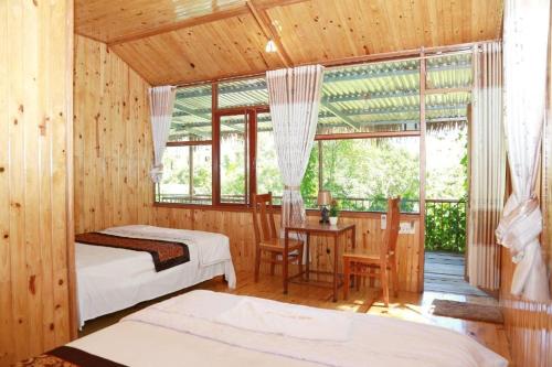 峰牙Phong Nha Midtown hotel的一间卧室设有两张床、一张桌子和一个窗口