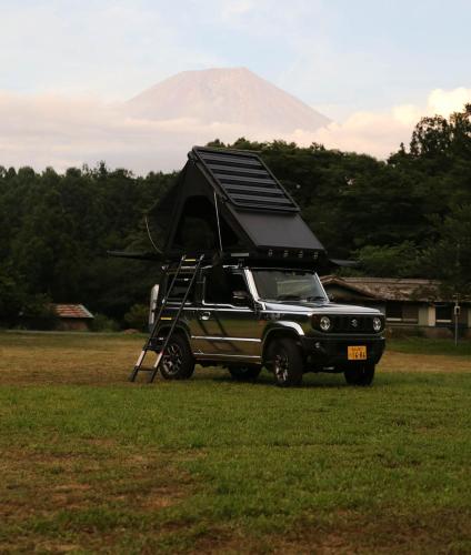 富士宫市FUUUN S Camping Car的停在田野上的吉普车,上面有帐篷