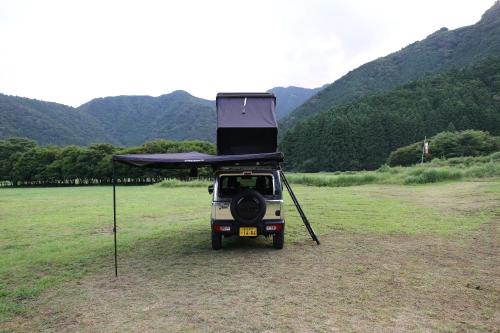 富士宫市FUUUN S Camping Car的停在一个有天篷的田野里的小型汽车
