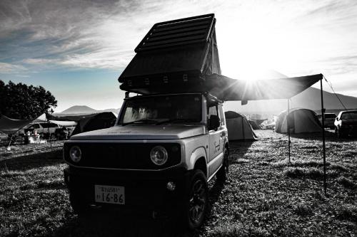 富士宫市FUUUN S Camping Car的一辆卡车停在一个有帐篷的田野里