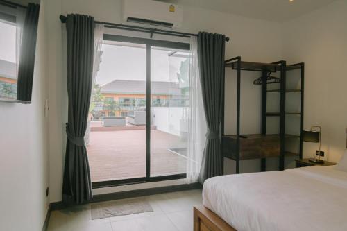 芭堤雅市中心ONE LODGE Pattaya的一间卧室设有一张床和一个滑动玻璃门