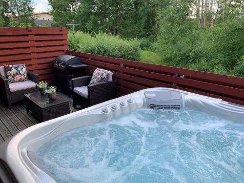 MynämäkiPieni lomahuoneisto ja ulkoporeallas的甲板上的热水浴池,配有2把椅子和烧烤架